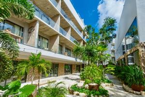 a building with trees and plants in front of it at Tuk Hacienda Studio Rooftop Pool Padel TUK in Tulum