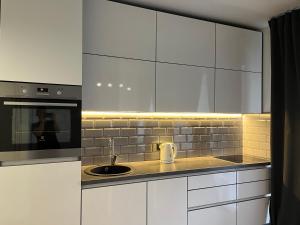 a kitchen with white cabinets and a sink and a microwave at Near Ozas Studio in Vilnius