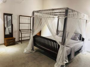 a bedroom with a canopy bed with mosquito nets at Oshi villa in Unawatuna