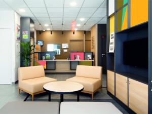 a waiting room with two chairs and a table and a tv at B&B HOTEL Paris Est Bobigny Université in Bobigny