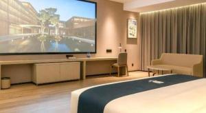 a hotel room with a large tv and a bed at Echarm Hotel Xiangyang Erqi in Xiangfanbei