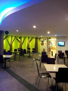 a restaurant with tables and chairs and a green wall at Casuarina Hotel in Kota Kinabalu