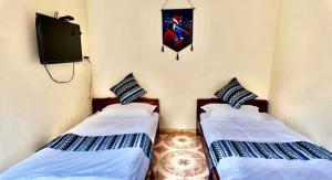 two beds in a room with a tv on the wall at Lien Huong Hostel in Ha Giang +5 photos