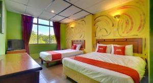 a hotel room with two beds and a tv at OYO 90929 DJ Hotel in Kampung Damar Laut