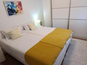 - une chambre avec un grand lit et une couverture jaune dans l'établissement Apartmani Jasmina 2, à Bihać