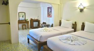 ナーンにあるNan Lanna Hotelのベッドが2つと鏡があるホテルの部屋