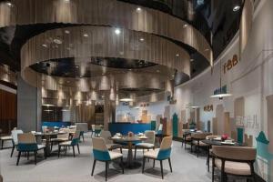 Hangzhou Qiantang Shama Hotel في Xinwan: غرفة طعام بها طاولات وكراسي وسقف