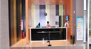 a lobby with a counter with two people in a room at Jinjiang Inn Luoyang Nanchang Road Wangfujing in Luoyang