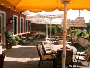 eine Außenterrasse mit Tischen, Stühlen und einem Sonnenschirm in der Unterkunft Landgasthof Franz Josef in Strasswalchen