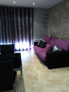 a purple couch in a living room with a stone wall at Cal Farre in Arbeca