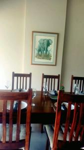 a dining room with a wooden table with a bear picture on the wall at Fikani game lodge in Thabazimbi