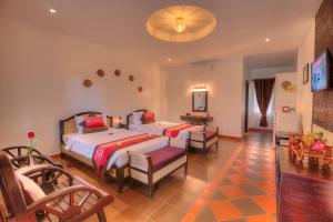 Kravan Siem Reap Boutique Villa في Phumĭ Kruŏs: غرفة نوم بها سريرين وتلفزيون بداخلها