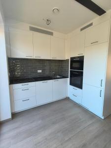 a kitchen with white cabinets and black appliances at Hof van Sassenbroek in Borgloon +26 photos