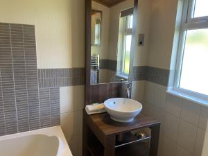 a bathroom with a sink and a tub and a mirror at Field View 2 bed - Hazel in Horham