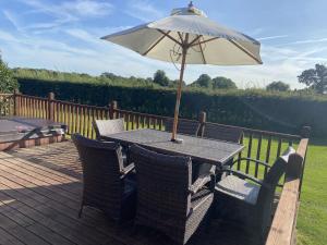 a table with an umbrella and chairs on a deck at Field View 2 bed - Hazel in Horham