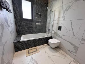 a bathroom with a toilet and a tub and a sink at Modern 3 bedroom villa with pool in Paphos City