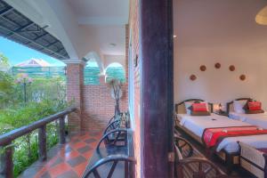 a balcony with two beds in a room with a balcony at Kravan Siem Reap Boutique Villa in Phumĭ Kruŏs
