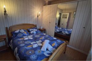 een slaapkamer met een bed met een blauw dekbed en een spiegel bij La maison du coeur in Coudekerque-Branche