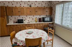 een keuken met een tafel, stoelen en een magnetron bij La maison du coeur in Coudekerque-Branche
