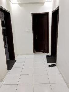 a hallway with two doors and a white tile floor at وادي جليل in As Sifyānī