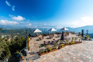 an outdoor patio with tables and chairs and umbrellas at Himalaya Drishya Resort in Dhulikhel
