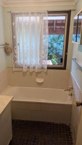 a bathroom with a white tub and a window at Bidwill Garden in Bidwill +3 photos