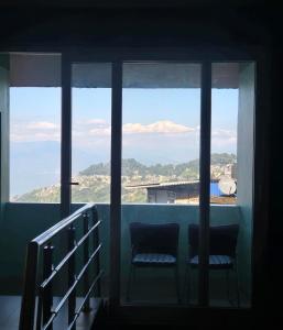 uitzicht op de bergen vanuit een raam met twee stoelen bij Sonali Megh in Darjeeling