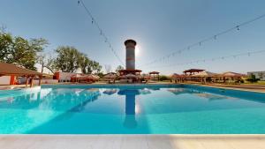 een groot zwembad met een vuurtoren op de achtergrond bij Royal Hotel & Events in Băileşti