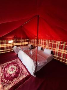 Al QārinOcean Camp的房间里有一张红色四柱床，铺着地毯。
