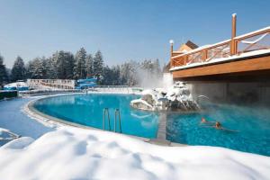 a swimming pool covered in snow with people in it at Apartma Roglina in Zreče +5 photos