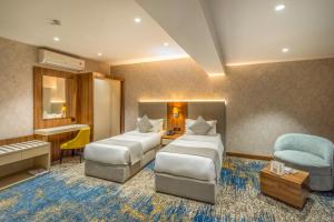 a hotel room with two beds and a chair at Haven Plaza Olaya By Tijan Co in Riyadh +76 photos