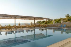 a pool with chairs and tables and a view of the ocean at Lalloudes Hotel Mani in Éxo Nímfion