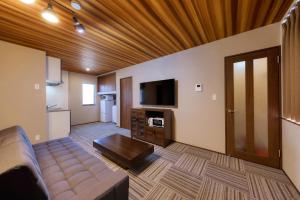 un salon avec un canapé et une télévision à écran plat dans l'établissement 又楽坊 Matarakubo, à Fujiyoshida