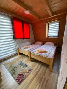 a small room with a bed and two windows at Apartmani Stajko in Crni Vrh
