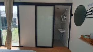 a bathroom with a glass door leading to a sink at ธัญญ์ รีสอร์ท หินดาด in Ban Pak Nam Chumphon