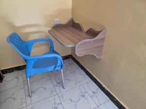 Civara Guest House في Kinancha: كرسي ازرق ومكتب في الغرفة