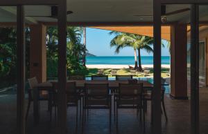 ein Esszimmer mit einem Tisch und Strandblick in der Unterkunft Bikini Bottom Villa by Utalay Koh Chang in Ban Khlong Son