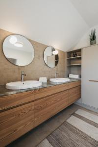 a bathroom with two sinks and two mirrors at Das Dietrich - Landhaus 62 in Leibnitz