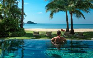 Ein Mann im Schwimmbecken blickt auf den Strand hinaus. in der Unterkunft Bikini Bottom Villa by Utalay Koh Chang in Ban Khlong Son