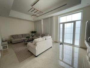 Villa في Sabkhah: غرفة معيشة مع أريكة بيضاء ونافذة كبيرة