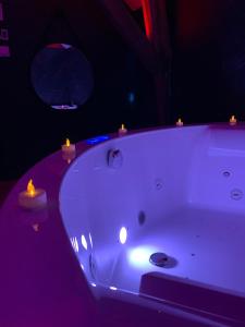 a white bath tub with candles on top of it at Love room avec jacuzzi privé in Bonnétable
