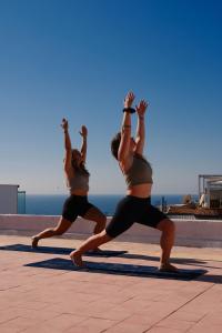 two women doing a yoga pose near the ocean at Catamaran Surf House in Agadir nʼ Aït Sa