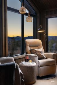 a living room with a chair and a table and windows at Ny og moderne hytte med sauna, jacuzzi og eget spillrom med biljard og dart Gratis elbillading og strøm inkludert i prisen in Flå