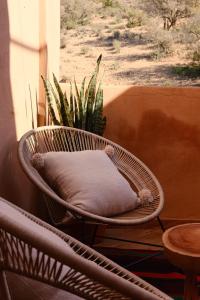 a wicker chair with a pillow in front of a window at Catamaran Surf House in Imi Ouaddar
