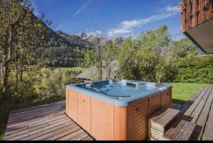 a hot tub on a deck with a view of the mountains at Chalet Papillon in La Chapelle-dʼAbondance