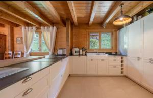 a large kitchen with white cabinets and a sink at Chalet Papillon in La Chapelle-dʼAbondance +7 photos