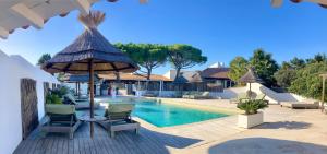 een zwembad in een resort met stoelen en een parasol bij Hôtel Spa Mas des Rièges in Saintes-Maries-de-la-Mer