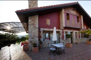 a building with a table and a umbrella on a patio at Hotel Katxi in Morga