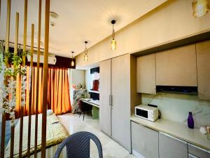 Nabhay Hotels and Resorts في غازي آباد: غرفة معيشة مع مطبخ مع ميكروويف