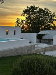 a house with a pool and a table and an umbrella at Casa no Montinho in Ourique